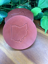 Load image into Gallery viewer, circular leather coaster brown with the state of ohio stamped in the middle

