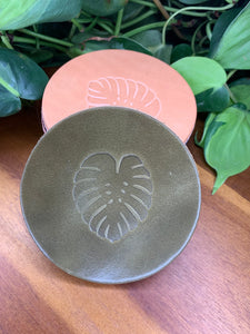 circular leather coaster olive with a monstera  leaf stamped in the middle