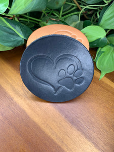 circular leather coaster black with a heart and paw print stamped in the middle