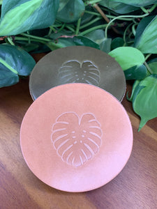 circular leather coaster tan with a monstera  leaf stamped in the middle