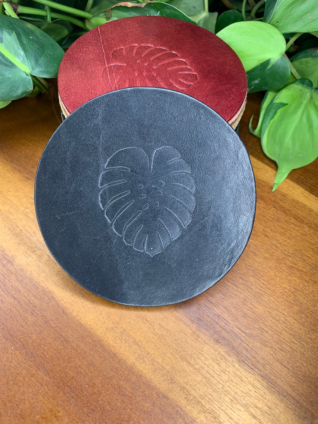 circular leather coaster black with a monstera  leaf stamped in the middle