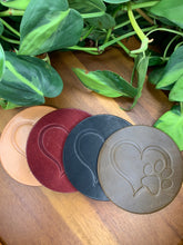 Load image into Gallery viewer, circular leather coaster burgundy black tan olive with a heart and paw print stamped in the middle
