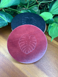 circular leather coaster burgundy with a monstera  leaf stamped in the middle